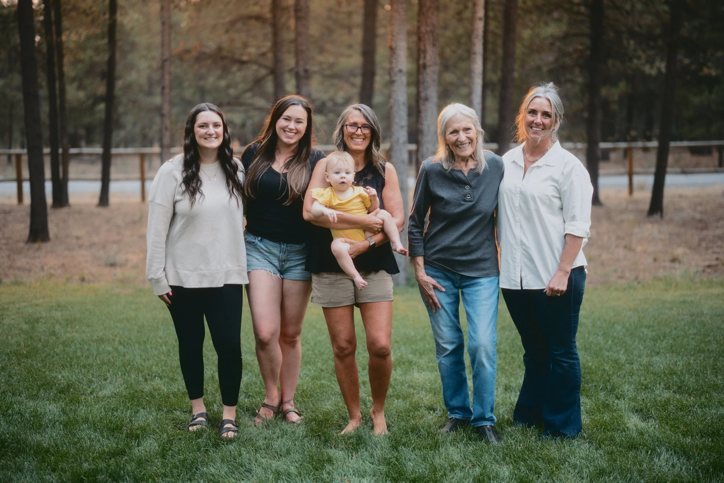 Extended family portrait with multiple generations standing together in a wooded setting.