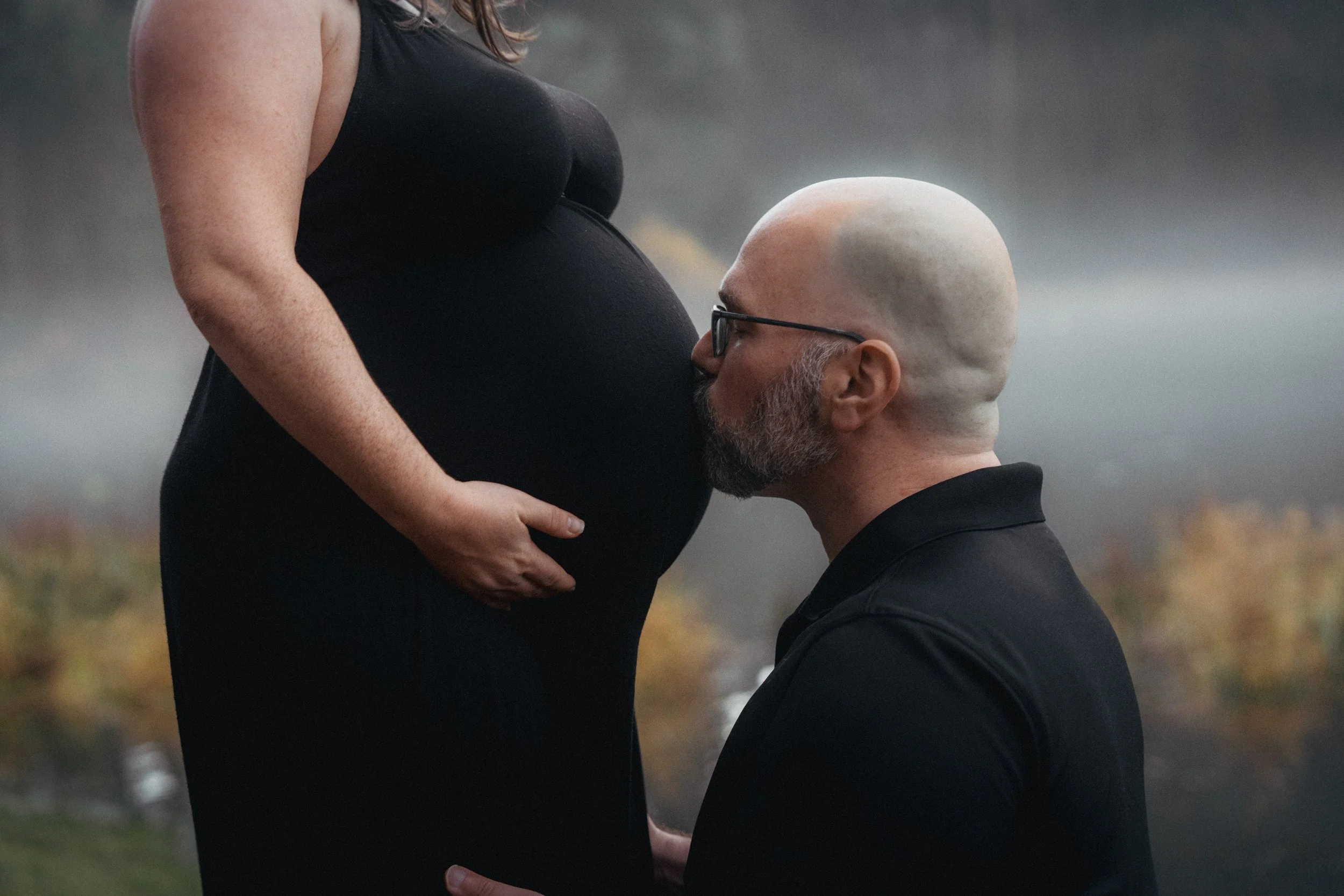 Expectant father kissing a pregnant belly during a maternity session.