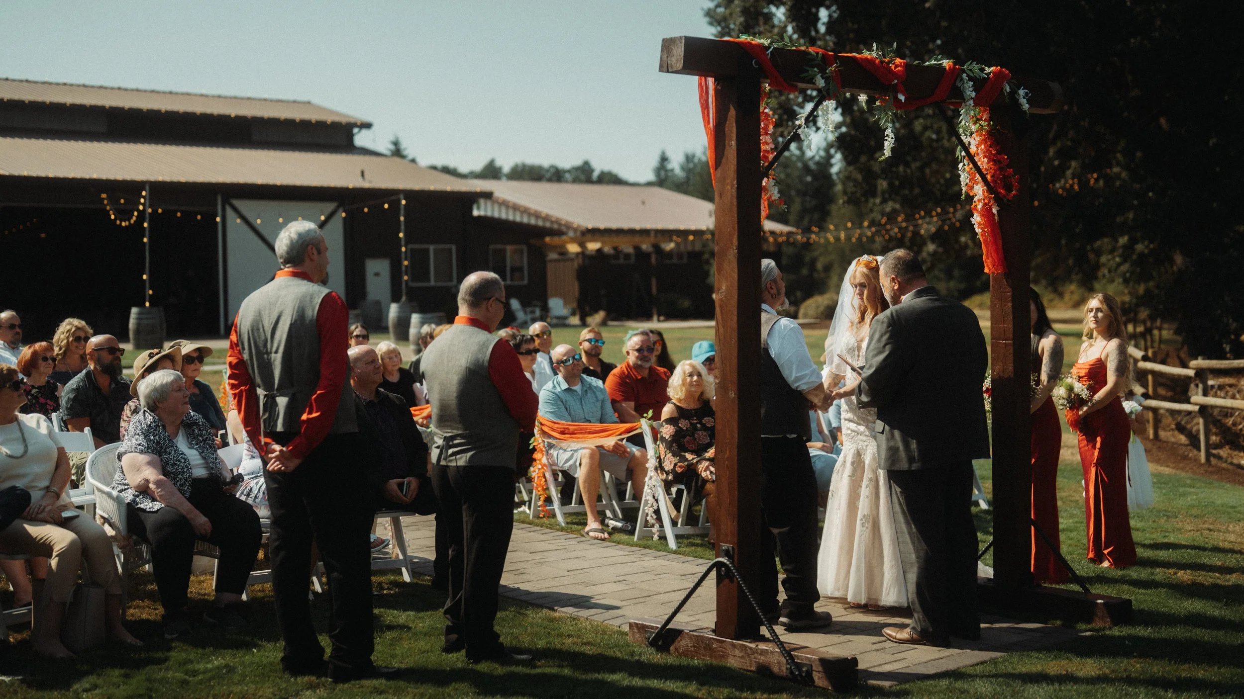 Outdoor wedding ceremony with bride and groom standing beneath a wooden arbor in Vancouver Washington.